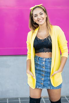 Happy woman wearing a yellow jacket and headband, near an urban purple wall