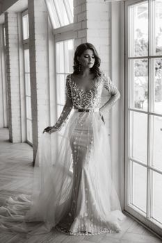 A luxurious bride in a wedding dress in the morning in her interior.Black and white photo.