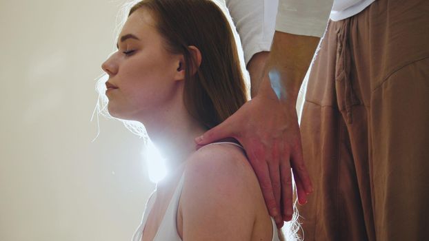 Male masseur processing the thai massage session for young attractive female model, close up