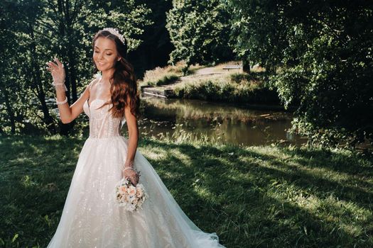 portrait of an elegant bride in a white dress with a bouquet in nature in a nature Park.Model in a wedding dress and gloves and with a bouquet .Belarus.