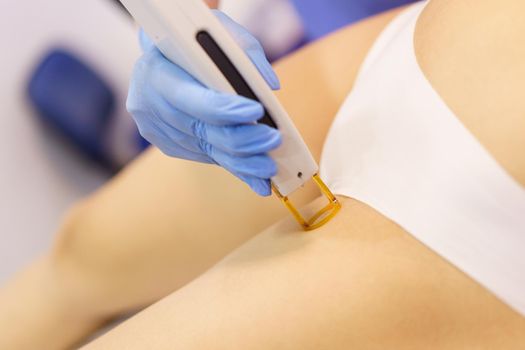 Woman receiving groins laser hair removal at a beauty center. Laser depilation treatment in an aesthetic clinic.