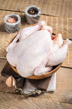 Organic chicken, raw poultry in a wooden plate. Wooden background. Top view.