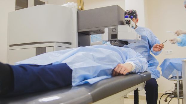 The patient lies on the operating surgical table during ophthalmology operation surgery wthout anesthesia - laser vision correction, horizontal