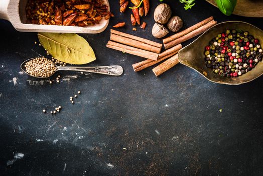 wooden spoons with spices and herbs on textured black table