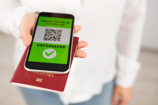 Woman holding passport and phone with qr code about vaccination