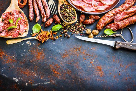 various sausages with spices on black table