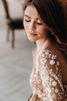 A luxurious bride in a wedding dress in the morning in her interior.