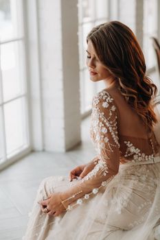 A luxurious bride in a wedding dress in the morning in her interior.