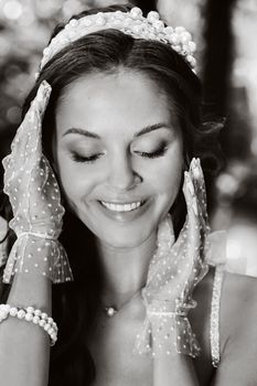 An elegant bride in a white dress, gloves with a bouquet on a waterfall in the Park, enjoying nature.Model in a wedding dress and gloves in the forest.Belarus.