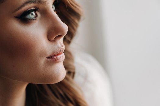 Close-up portrait of a luxurious bride in a wedding dress in the morning in her interior.