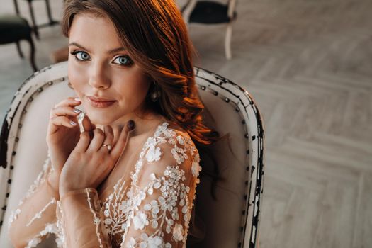 Close-up portrait of a luxurious bride in a wedding dress in the morning in her interior.