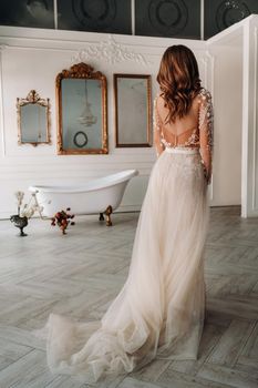 A luxurious bride in a wedding dress in the morning in her interior.