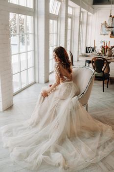 A luxurious bride in a wedding dress in the morning in her interior.