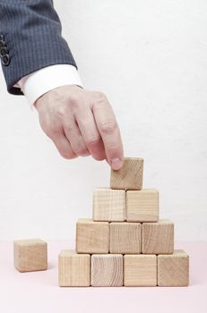 hand creating pyramid from wooden cubes