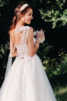 portrait of an elegant bride in a white dress with a bouquet in nature in a nature Park.Model in a wedding dress and gloves and with a bouquet .Belarus.