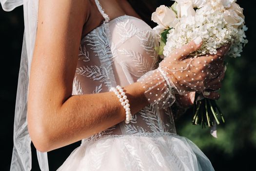 portrait of an elegant bride in a white dress with a bouquet in nature in a nature Park.Model in a wedding dress and gloves and with a bouquet .Belarus.