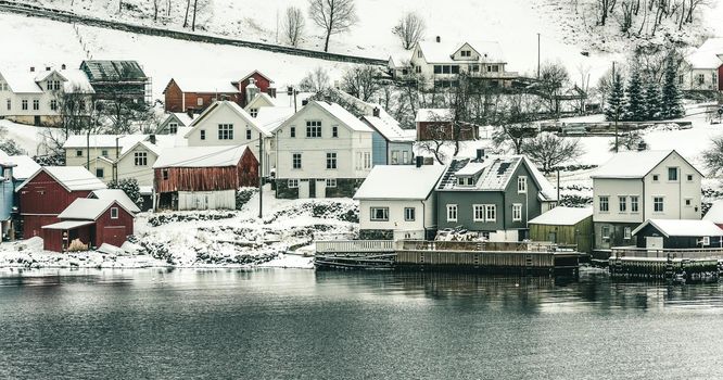 wooden houses on the banks of the Norwegian fjord, beautiful mountain landscape in winter