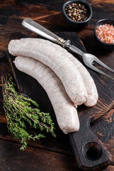 Munich traditional white sausages on a wooden board with thyme. Dark wooden background. Top view.