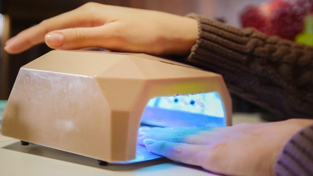 Working manicurist - drying nails in a special equipment for professional manicure, close up