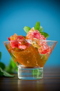 colored sweet fruit jelly in a glass glass on a wooden table