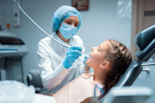 Side view of Female dentist who treats teeth of little child patient in dental office. Dentistry concept .