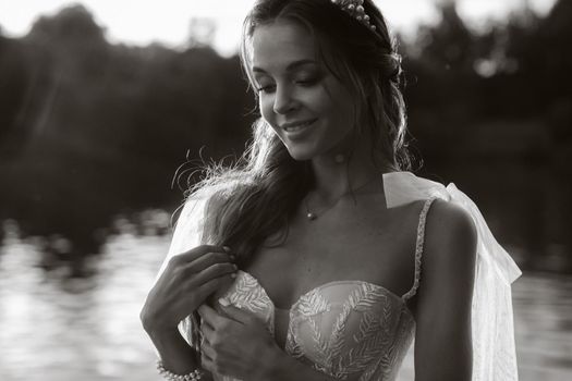 An elegant bride in a white dress enjoys nature at sunset.Model in a wedding dress in nature in the Park.Belarus.black and white photo.