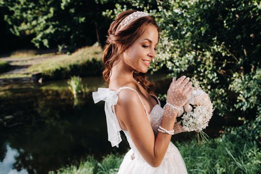 portrait of an elegant bride in a white dress with a bouquet in nature in a nature Park.Model in a wedding dress and gloves and with a bouquet .Belarus.