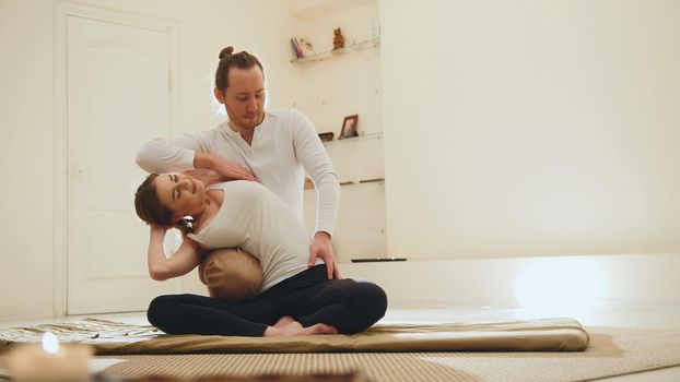 Thai massage session - traditional therapy for white young woman, horizontal