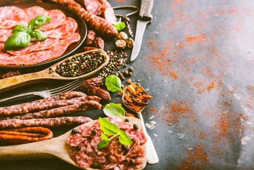 various sausages with spices on black table