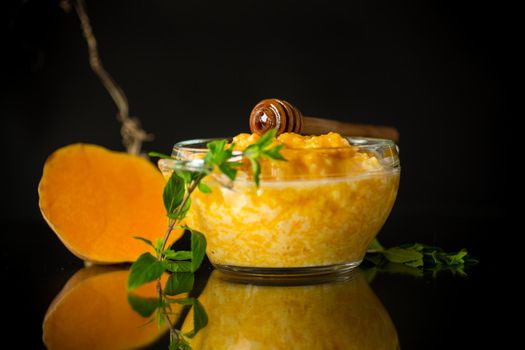 sweet boiled pumpkin porridge in a bowl with honey isolated on black background