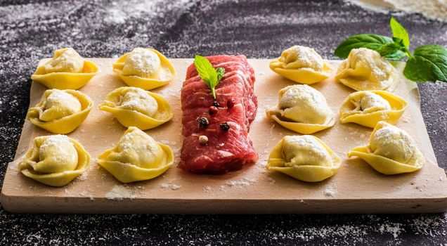 raw ravioli and different products on the black kitchen table