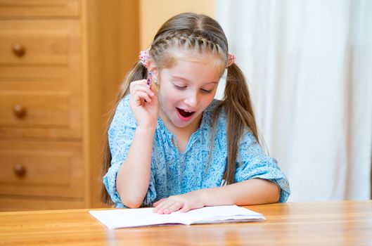Cute little girl studying at home and smiling