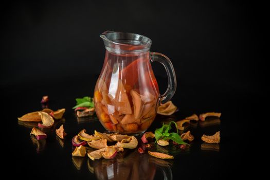 sweet cool compote boiled from various dried fruits, in a glass decanter on a black background