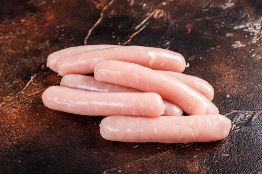 Raw chicken and turkey meat sausages on butcher table. Dark background. Top view.
