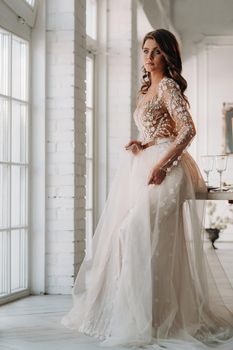 A luxurious bride in a wedding dress in the morning in her interior.