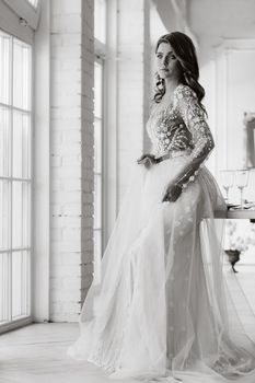 A luxurious bride in a wedding dress in the morning in her interior.Black and white photo.