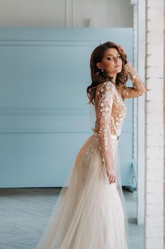 A luxurious bride in a wedding dress in the morning in her interior.