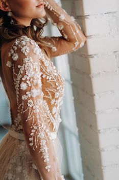 A luxurious bride in a wedding dress in the morning in her interior.