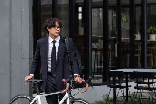 Asian businessman pushing his bicycle in the morning preparing to ride his bicycle to work. Eco tranportation.