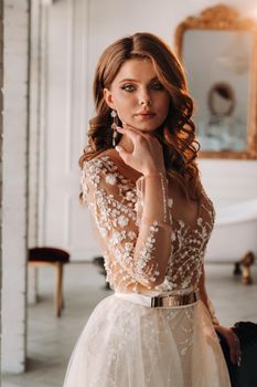 A luxurious bride in a wedding dress in the morning in her interior.