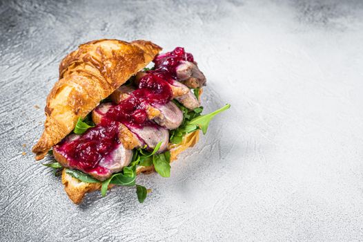 Duck breast Croissant sandwich with steak slices, arugula and sauce. White background. Top View. Copy space.