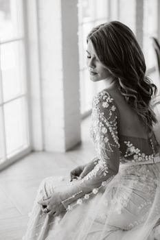 A luxurious bride in a wedding dress in the morning in her interior.Black and white photo.