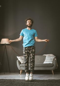 A young man jumps on a rope at home. The quarantine pandemic sports concept. High quality photo.