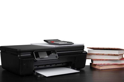Printer and stack of books on black table against white background, close up