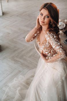 A luxurious bride in a wedding dress in the morning in her interior.