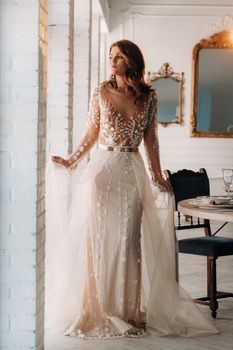 A luxurious bride in a wedding dress in the morning in her interior.