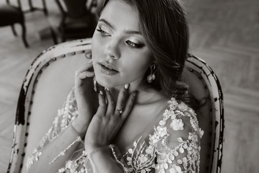 Close-up portrait of a luxurious bride in a wedding dress in the morning in her interior.black and white photo.