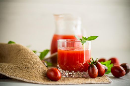homemade freshly squeezed tomato juice with pulp in a glass decanter, on a wooden table.