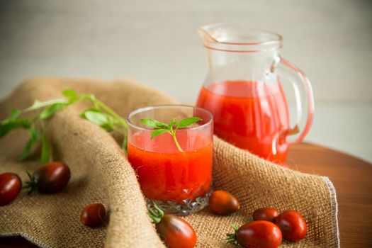 homemade freshly squeezed tomato juice with pulp in a glass decanter, on a wooden table.