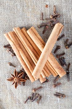 fragrant cinnamon, dry cloves and anise star on a piece of linen tablecloth on a wooden cutting board, table details in the kitchen